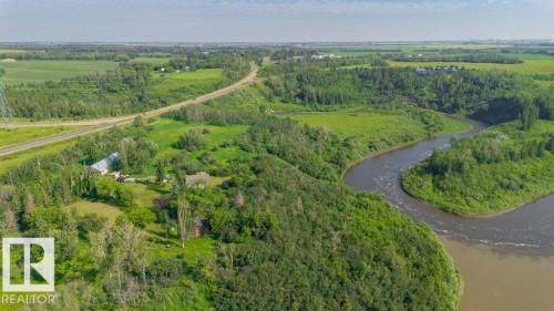 Expansive acreage featuring a winding river, dense woodland, open fields, a paved road, and visible structures - 55319 Rge Road 222, Rural Sturgeon County, AB 