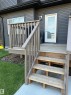Rear patio with wood decking and painted wood railings, featuring a full-light back door with a white frame - #2 2710 66 St Sw, Edmonton, AB  - Outdoor With Deck Patio Veranda With Exterior 