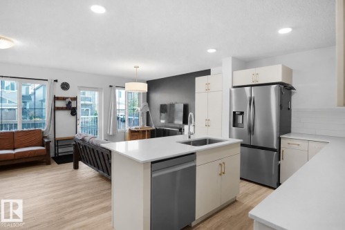 Modern kitchen island with an undermount sink, quartz countertop, and stainless steel dishwasher - #42 19904 31 Av Nw, Edmonton, AB - Indoor Photo Showing Kitchen With Upgraded Kitchen