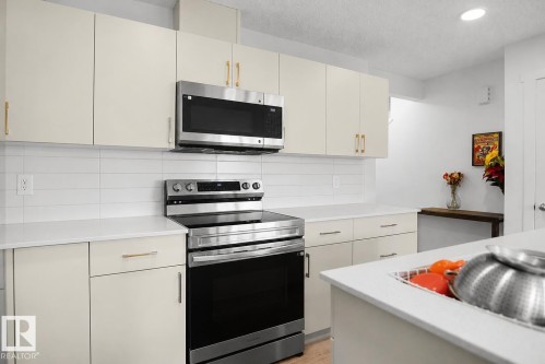 Modern kitchen featuring white shaker-style cabinetry with gold-tone hardware, white subway tile backsplash, and recessed lighting - #42 19904 31 Av Nw, Edmonton, AB - Indoor Photo Showing Kitchen