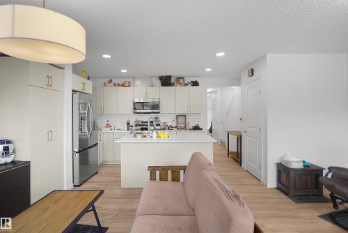 Kitchen featuring stainless steel appliances, white cabinetry with gold-tone hardware, a white subway tile backsplash, and a central island with a white countertop - #42 19904 31 Av Nw, Edmonton, AB - Indoor Photo Showing Kitchen With Upgraded Kitchen
