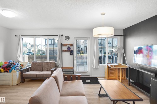Living area featuring light wood-finish flooring, white walls, and a partial accent wall with a dark finish - #42 19904 31 Av Nw, Edmonton, AB - Indoor Photo Showing Living Room