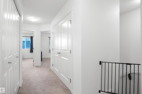 Carpeted hallway featuring white walls, white doors, and a flush mount ceiling light - #42 19904 31 Av Nw, Edmonton, AB - Indoor Photo Showing Other Room