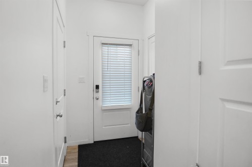 Entryway featuring a white paneled door with integrated window blinds, a smart lock, and wood-finish flooring - #42 19904 31 Av Nw, Edmonton, AB - Indoor Photo Showing Other Room