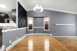 Kitchen and living area featuring wood-finish flooring, vaulted ceilings, and a decorative half-wall with patterned wallpaper - 