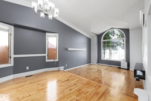 Interior space featuring polished wood-finish flooring and a contemporary chandelier - 4639 10 Avenue Nw, Edmonton, AB - Indoor Photo Showing Other Room