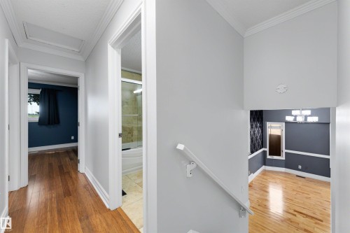 Hardwood flooring throughout the hallway and room, featuring crown molding, baseboards, and a built-in bathroom with a shower and tub - 4639 10 Avenue Nw, Edmonton, AB - Indoor Photo Showing Other Room