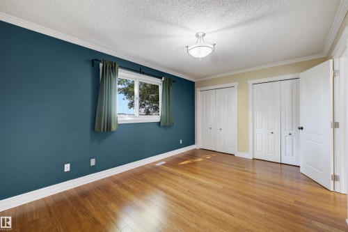 Hardwood-style flooring extends throughout this room, featuring a double window with green drapes - 4639 10 Avenue Nw, Edmonton, AB - Indoor Photo Showing Other Room