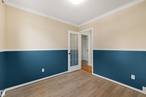 Room featuring two-tone walls with white trim, wood-finish flooring, and a white ceiling with crown molding - 4639 10 Avenue Nw, Edmonton, AB - Indoor Photo Showing Other Room