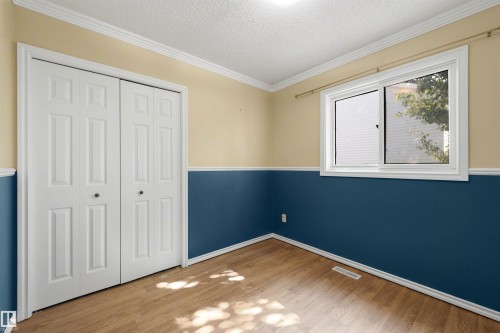 Room featuring wood-finish flooring, white bi-fold closet doors, a single window, crown molding, and baseboards - 4639 10 Avenue Nw, Edmonton, AB - Indoor Photo Showing Other Room