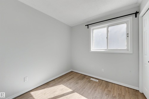 Neutral wall paint with crown molding and wood-finish flooring - 4639 10 Avenue Nw, Edmonton, AB - Indoor Photo Showing Other Room