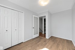 Interior room featuring wood-finish flooring, light grey painted walls, white bi-fold closet doors, and white baseboards - 