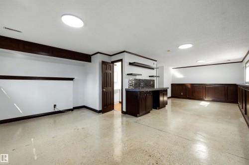 Spacious room featuring light-colored flooring, white walls, and dark wood trim - 4639 10 Avenue Nw, Edmonton, AB - Indoor Photo Showing Other Room
