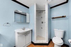 Bathroom featuring a white vanity with integrated sink, a medicine cabinet, a tiled shower enclosure, and terracotta-style floor tiles - 