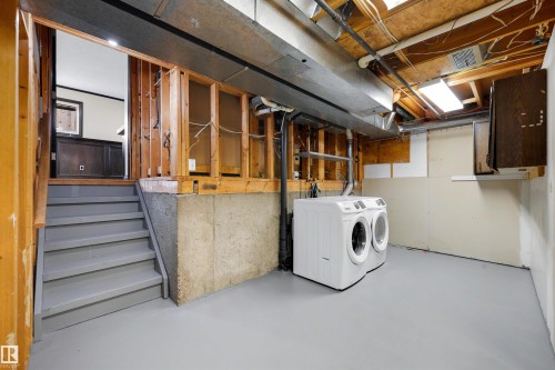 Lower-level utility area featuring painted concrete flooring, an exposed ceiling with visible joists and ductwork, and a partial staircase with painted treads - 4639 10 Avenue Nw, Edmonton, AB - Indoor Photo Showing Laundry Room