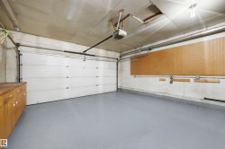 Attached garage featuring an automatic overhead door, gray epoxy flooring, built-in wooden cabinetry, and wall-mounted pegboard for organization - 