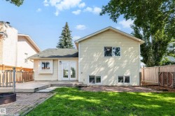 Rear exterior featuring light-colored siding, a dark shingle roof, and multiple windows - 