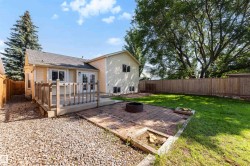 Rear exterior featuring a wood deck, brick patio, and expansive green lawn - 