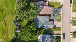 Aerial perspective showcasing a residential property with a shingle roof and a spacious backyard - 