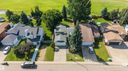 Residential property with a spacious backyard featuring a manicured lawn and mature trees - 