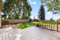 Expansive backyard featuring a wood deck, brick patio, mature trees, manicured lawn, and privacy fencing - 