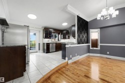 Kitchen and dining area featuring a tile and wood-finish flooring transition, dark wood cabinetry, stainless steel appliances, a white tile backsplash, and a contemporary chandelier - 