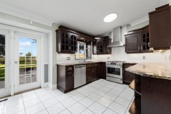 Kitchen featuring dark wood cabinetry, granite countertops, and stainless steel appliances - 