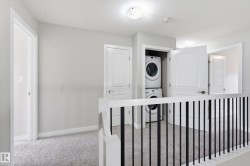 Second-story hallway featuring light gray walls, plush gray carpeting, and white trim - 