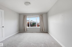 Bright room with neutral gray walls, light gray carpeting, and a large window featuring white trim - 