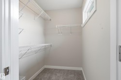 Walk-in closet featuring wire shelving, hanging rods, and an upper window - 