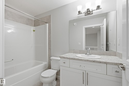 Bathroom featuring a white vanity with a light-toned countertop, an undermount sink, and brushed nickel hardware - 1860 Keene Crescent Sw, Edmonton, AB - Indoor Photo Showing Bathroom