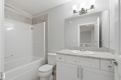 Bathroom featuring a white vanity with a light-toned countertop, an undermount sink, and brushed nickel hardware - 
