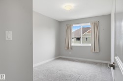 Carpeted room featuring a large window, neutral wall paint, white trim, and a ceiling-mounted light fixture - 