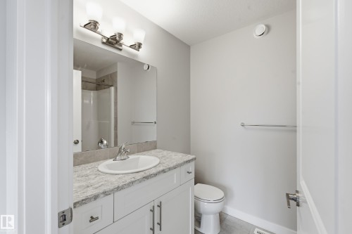 Bathroom featuring a white vanity with a light-toned countertop, an integrated sink, and a large wall-mounted mirror - 1860 Keene Crescent Sw, Edmonton, AB - Indoor Photo Showing Bathroom