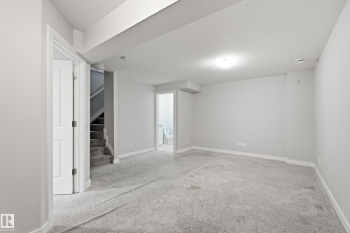 Spacious carpeted room featuring light gray walls, white baseboards, and a flush-mount ceiling light - 1860 Keene Crescent Sw, Edmonton, AB - Indoor Photo Showing Other Room