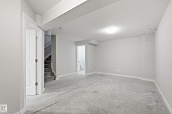 Spacious carpeted room featuring light gray walls, white baseboards, and a flush-mount ceiling light - 