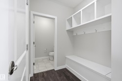 Built-in storage bench with overhead cubbies and coat hooks, complemented by dark wood-finish flooring - 
