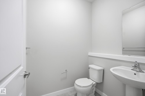 Guest bathroom with a pedestal sink, wall-mounted mirror, and tile flooring - 1860 Keene Crescent Sw, Edmonton, AB - Indoor Photo Showing Bathroom