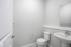 Guest bathroom with a pedestal sink, wall-mounted mirror, and tile flooring - 