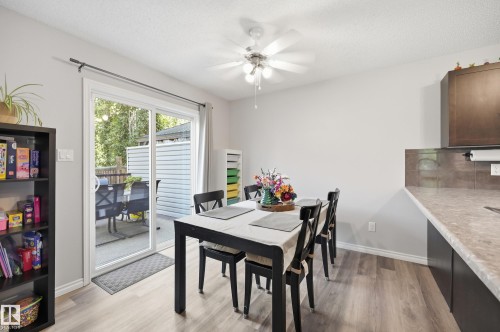 Bright dining area featuring sliding glass patio doors, wood-finish flooring, and a ceiling fan with integrated lighting - 3606 Whitelaw Bay Nw, Edmonton, AB - Indoor Photo Showing Dining Room
