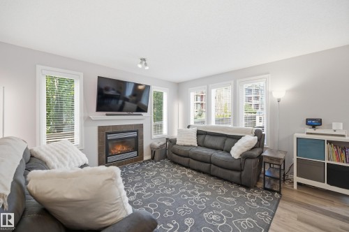 Living area featuring a tiled fireplace with a mantel, multiple windows with blinds, and light-toned walls - 3606 Whitelaw Bay Nw, Edmonton, AB - Indoor Photo Showing Living Room With Fireplace