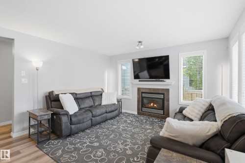Living area featuring wood-finish flooring, light grey walls, and white trim - 3606 Whitelaw Bay Nw, Edmonton, AB - Indoor Photo Showing Living Room With Fireplace