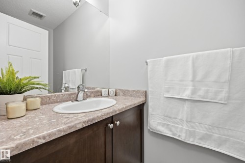 Bathroom vanity featuring an integrated oval sink, single-handle faucet, and stone-look countertop - 3606 Whitelaw Bay Nw, Edmonton, AB - Indoor Photo Showing Bathroom