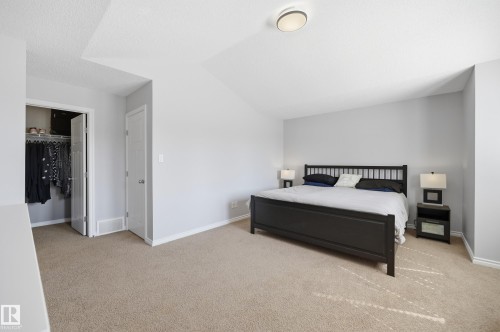 Carpeted bedroom featuring light gray walls, a built-in closet with bi-fold doors, and a ceiling-mounted light fixture - 3606 Whitelaw Bay Nw, Edmonton, AB - Indoor Photo Showing Bedroom