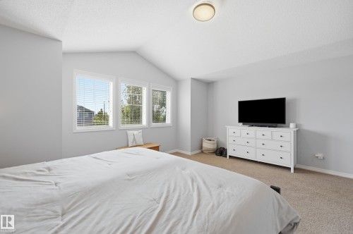 Vaulted ceiling room featuring three windows with horizontal blinds, light gray wall paint, and neutral carpet flooring - 3606 Whitelaw Bay Nw, Edmonton, AB - Indoor Photo Showing Bedroom