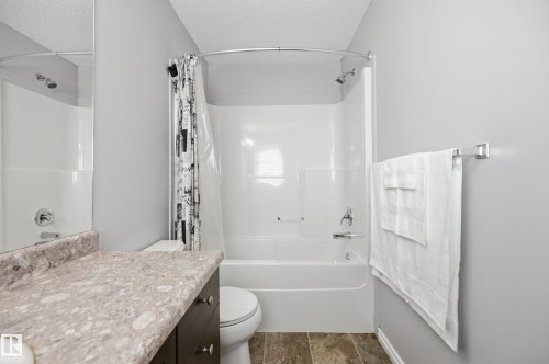 Full bathroom featuring a white tub/shower combination, a dark wood-finish vanity with a patterned countertop, and light gray wall paint - 3606 Whitelaw Bay Nw, Edmonton, AB - Indoor Photo Showing Bathroom