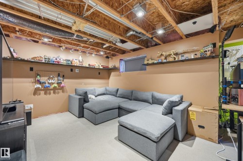 Carpeted recreation area featuring exposed ceiling joists, a built-in wall shelf, recessed lighting, and a window opening - 3606 Whitelaw Bay Nw, Edmonton, AB - Indoor Photo Showing Basement