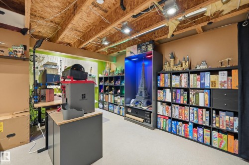 Finished basement space featuring exposed wooden ceiling joists with recessed lighting, light-colored carpeting, built-in shelving units, and a dedicated workspace - 3606 Whitelaw Bay Nw, Edmonton, AB - Indoor