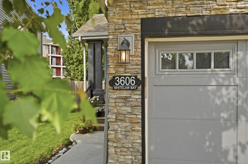 Stone veneer exterior featuring a gray paneled garage door with transom windows - 3606 Whitelaw Bay Nw, Edmonton, AB - Outdoor