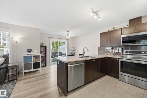 Modern kitchen featuring dark wood-finish cabinetry, stainless steel appliances, and a tile backsplash - 3606 Whitelaw Bay Nw, Edmonton, AB - Indoor Photo Showing Kitchen With Double Sink